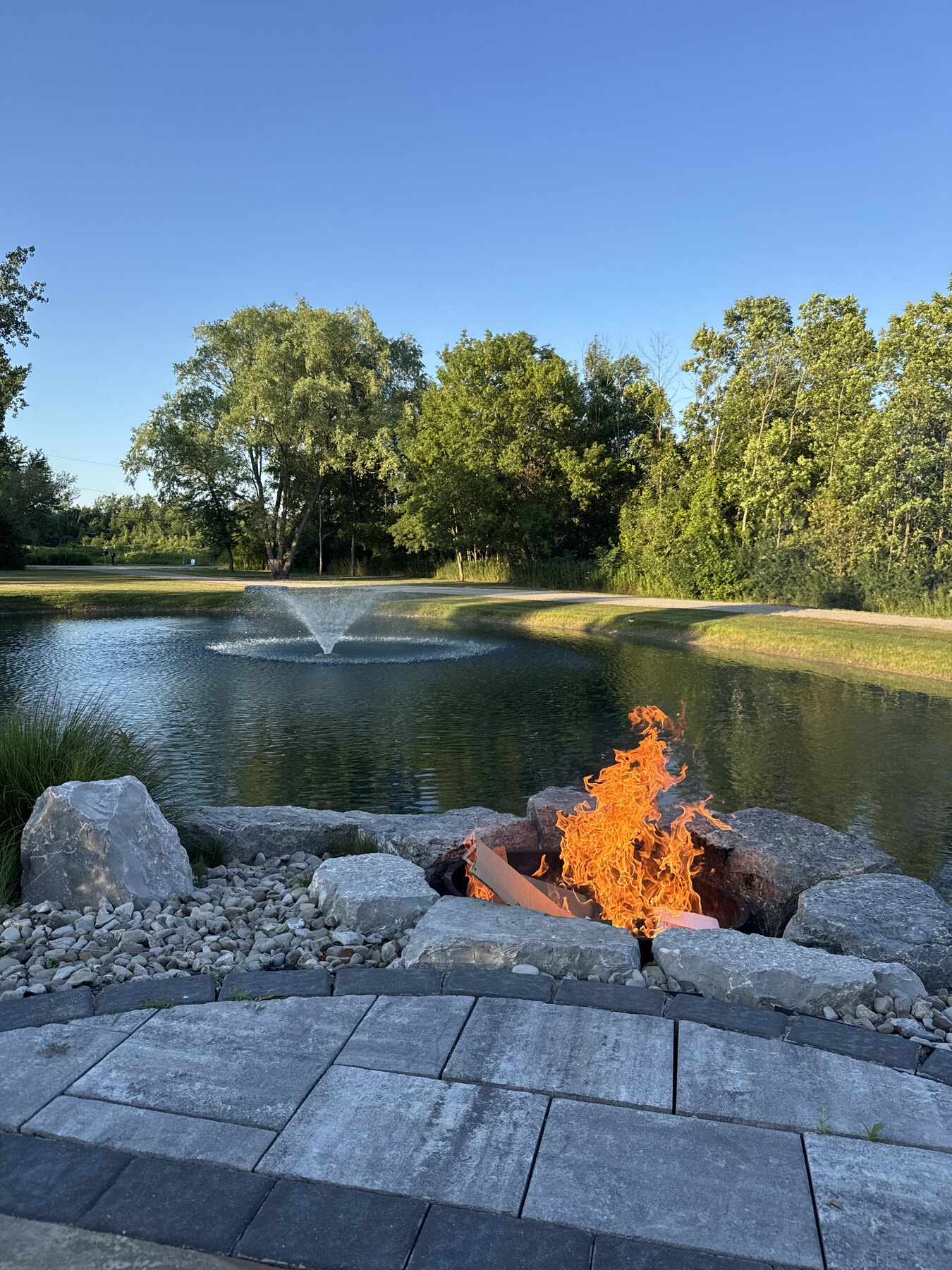 Fire pit overlooking the private pond and fountain, framed by mature trees at 1585 Davis Road